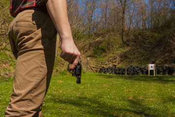 Unrecognizable man with revolver preparing to shot target on shooting range outdoors.