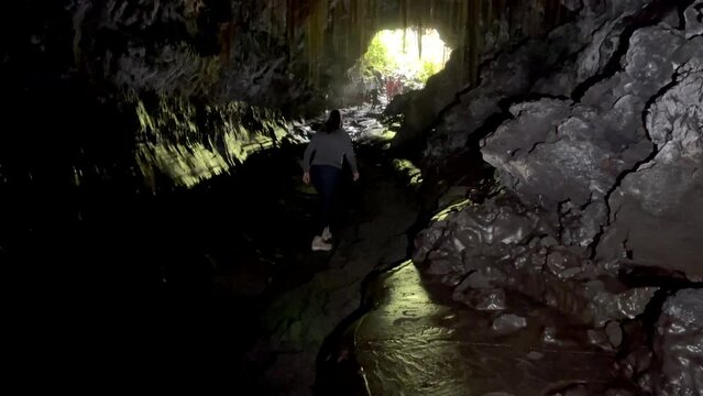 Lady walking and exploring the Kaumana Cave in Hawaii. Lava tube from Mauna Loa volcano