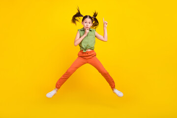 Fototapeta na wymiar Photo of shiny serious student girl wear green shirt smiling jumping high finger lips asking keeping silence isolated yellow color background