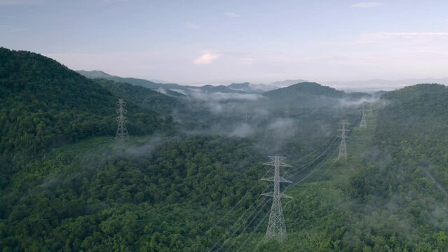Video 4K, Aerial view Morning scenic on high mountains with electricity pylon Pang Puay, Mae Moh, Lampang, Thailand. Beautiful morning with golden sunrise and fog flowing.