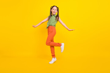 Fototapeta na wymiar Photo of excited funky student girl wear green shirt smiling walking isolated yellow color background