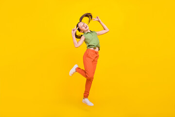 Photo of charming cheerful preteen girl dressed green top jumping high showing two v-signs smiling...