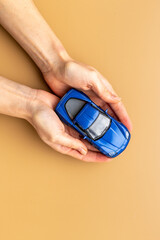 Toy car in hands, top view. Car insurance or driving safety concept