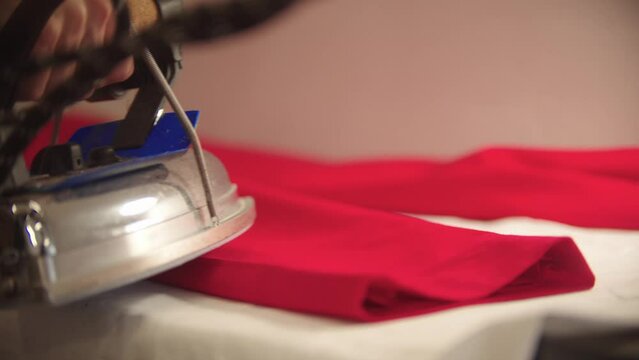 A woman designer ironing red fabric