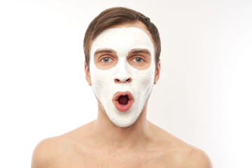 Portrait of young handsome man with cosmetic mask on his face isolated on white background