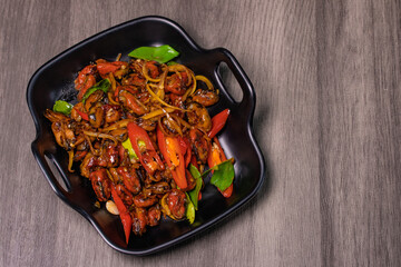 Spicy stir-fried mussels in a black dish.Thai food