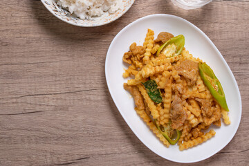 Stir-fried pork with red curry paste and young coconut shoots in a white plate