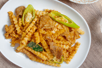 Stir-fried pork with red curry paste and young coconut shoots in a white plate