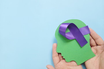 Hand holding human head profile with purple awareness ribbon on brain. Alzheimer's Disease, ADHD,...