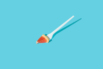 Composition made with citrus sliced with fork on sunny blue background. Creative heathy snack,...