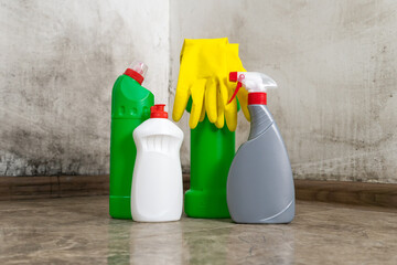 Close-up of cleaning products standing on the floor, yellow gloves for removing mold from the walls. Concept of cleaning, household chores