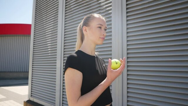 Lifestyle shot of a young attractive woman throwing up a tennis ball