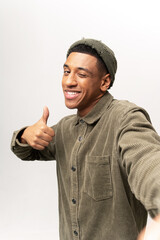 Portrait of young adult handsome man taking selfie, looking at camera POV and showing big finger gesture, point of view of photo. Indoor studio shot isolated on white background