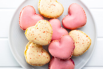 Heart shaped Sweet macarons on plate on white table.