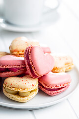 Heart shaped Sweet macarons on plate on white table.