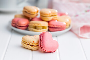 Heart shaped Sweet macarons on white table.