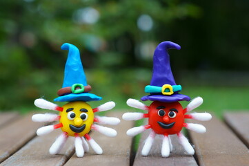 Virus figurines made of plasticine decorated with a festive hat. Ideas for Halloween. The symbol of the coronavirus.