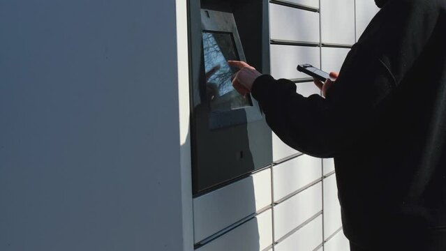 Unrecognizable woman Collecting parcel from shopping locker. Woman Skans QR Code on Mobile phone Self-service Locker Cell with Bar code Reader Modern Shipping and Delivery Concept with Contactless