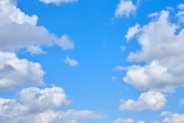 Naklejka na ściany i meble Background cumulus clouds against a blue sky illuminated by sunlight.