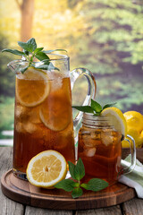 Pitcher and glass of ice tea with lemon slices and mint