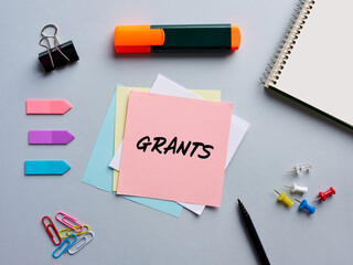 The word grants written on a notepaper on business office desktop. Funding or financial support in...