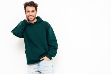 Handsome smiling hipster  model.Sexy unshaven man dressed in summer stylish green hoodie clothes. Fashion male with curly hairstyle posing in studio. Isolated on white