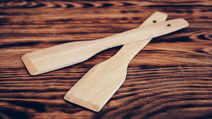 Wooden kitchen spatulas on brown table background