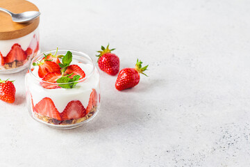 Strawberry parfait with yogurt and granola in glass jar. Healthy breakfast recipe. Summer dessert concept.