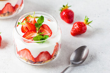 Strawberry parfait with yogurt and granola in glass jar. Healthy breakfast recipe. Summer dessert concept.