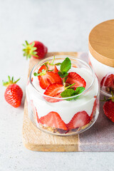 Strawberry parfait with yogurt and granola in glass jar. Healthy breakfast recipe. Summer dessert concept.