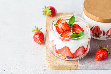 Strawberry parfait with yogurt and granola in glass jar. Healthy breakfast recipe. Summer dessert concept.