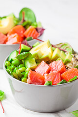 Hawaiian poke - brown rice, salmon, edamame, cucumber and avocado in gray bowl, marble background. Fish fresh salad for a healthy diet.