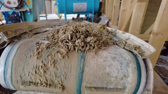 Close-up of fresh hempcrete falling from a conveyor belt into a box at slow-motion 60fps