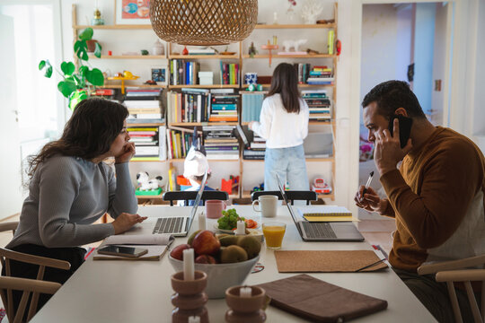 Man and woman working from home while children playing in living room