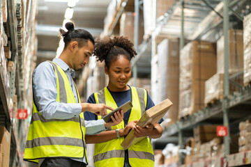male worker and an African American female worker wearing uniforms pick up a  box to count the...