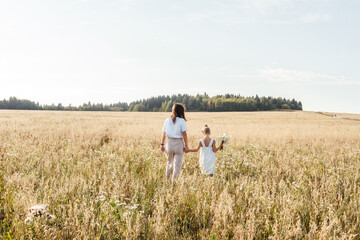 Naklejka na ściany i meble Young mother and daughter in field. Summer concept.