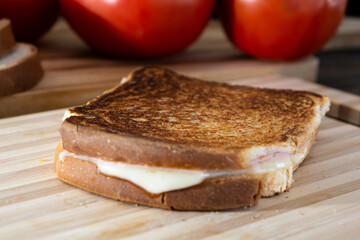 hot cheese sandwich made of cheese and ham on wooden surface