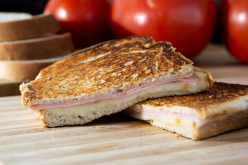 two halves or slices of hot cheese sandwich made of cheese and ham on wooden surface