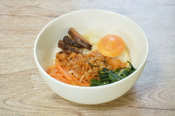 Bibimbub Korean food rice topping pickled sesame oil cabbage with slice carrot and mushroom dressing chop chicken in sauce couple egg on bowl