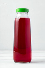 Small glass bottle of fresh juice on white background