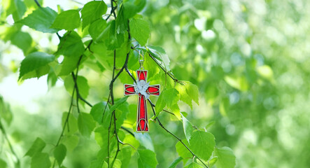 Christian cross with image of a dove on birch branches, blurred green natural background. symbol of...