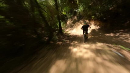 Mountain-bike rider riding fast at forest Trail Pathan followed by fpv drone 