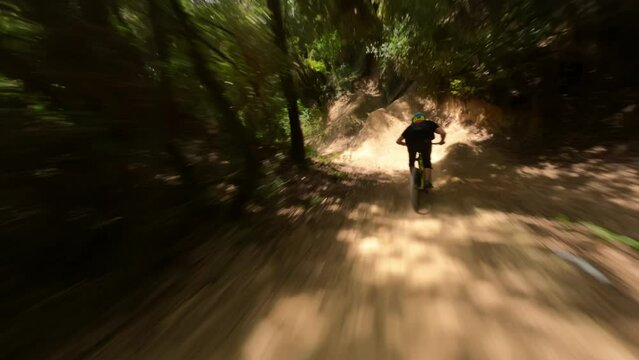 Mountain-bike rider riding fast at forest Trail Pathan followed by fpv drone 