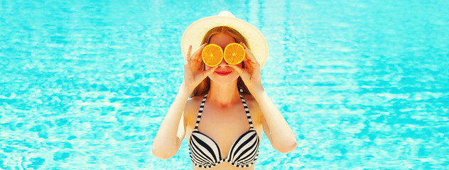 Summer sunny portrait smiling woman holds in hands oranges and hides his eyes on blue water pool...