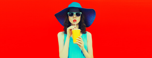 Fototapeta Portrait of beautiful young woman drinking fresh juice from cup wearing summer hat on red background, blank copy space for advertising text obraz
