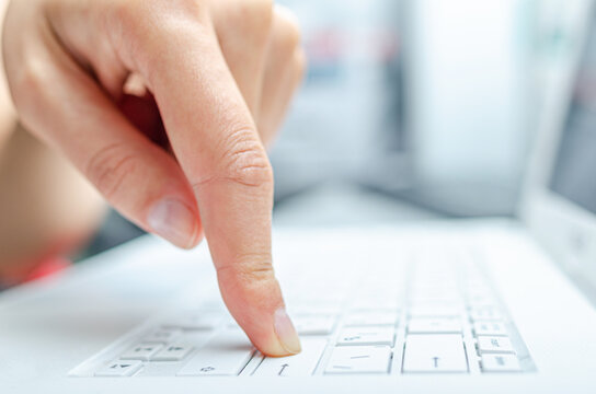 Human hands are typing on a white computer keyboard, close-up.
