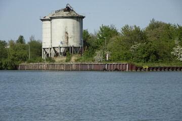 Big white metal silos and vegetation at Mittelland Canal (Mittellandkanal), sunny spring day...