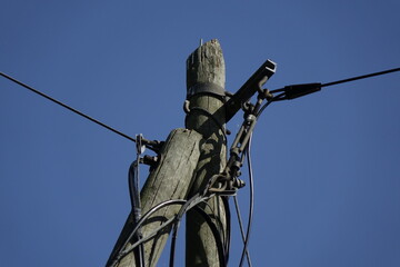 Obraz premium Wires and top of old wooden telegraph pole plus small cobbweb on the right side under a blue spring sky, concept: vintage, use: background, wallpaper, copy space (horizontal), Sehnde,Germany
