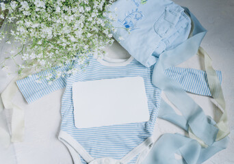postcard mockup on the background of baby newborn clothes in blue colors