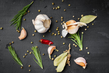 Garlic cloves and spices on black background